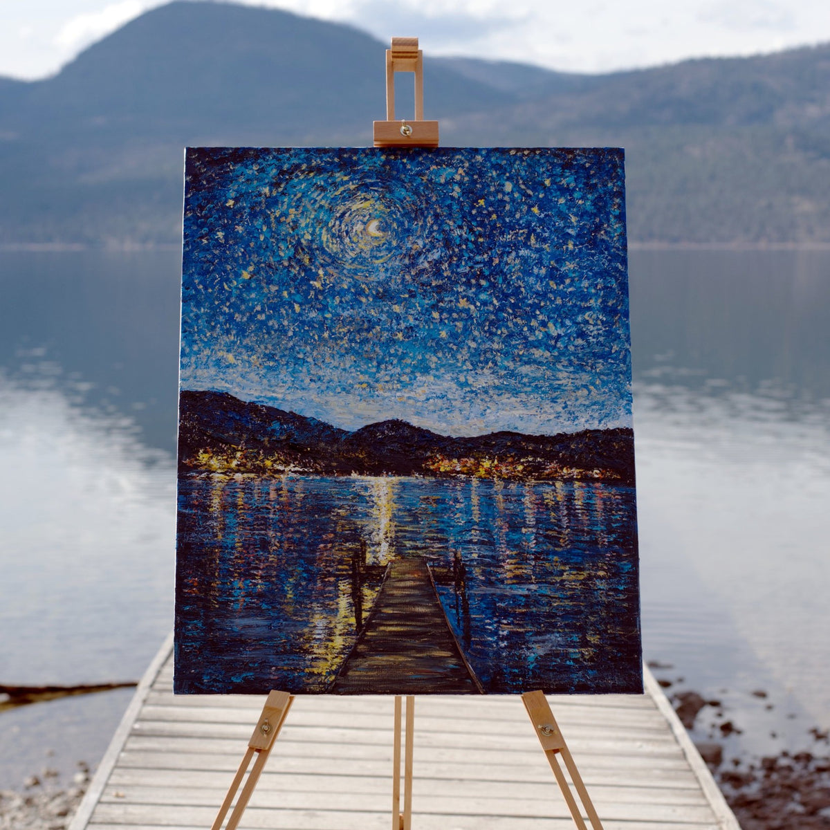 Okanagan Lake in Moonlight, an original painting by Zhongda Huang, on an easel on a dock at Okanagan Lake
