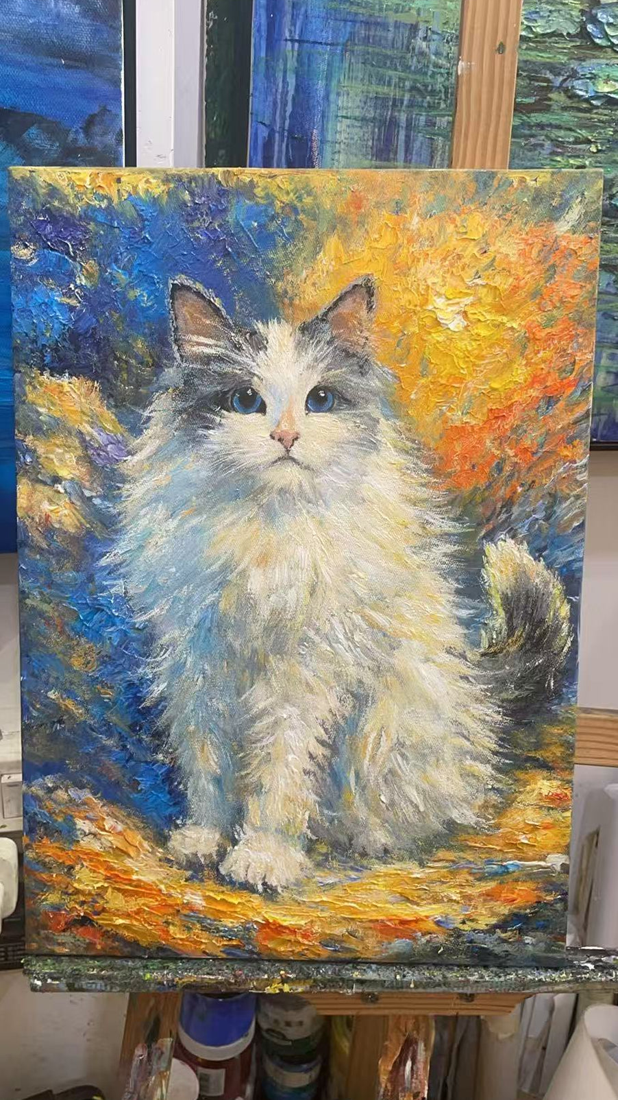 Painting of a cat on an easel with art supplies in the background