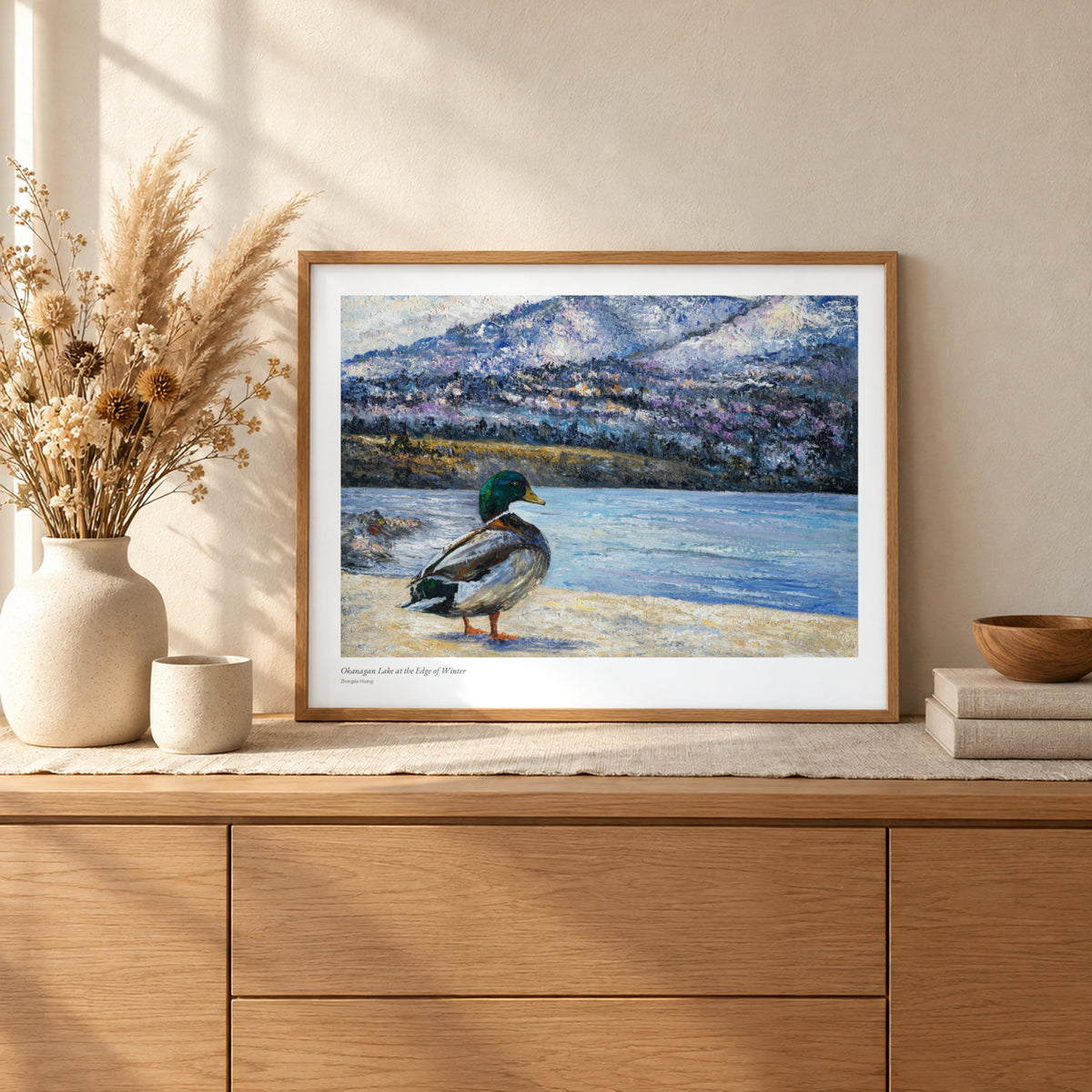 Okanagan Lake at the Edge of Winter studio print, 22 × 17 in, in a light oak frame on a sideboard (frame not included)