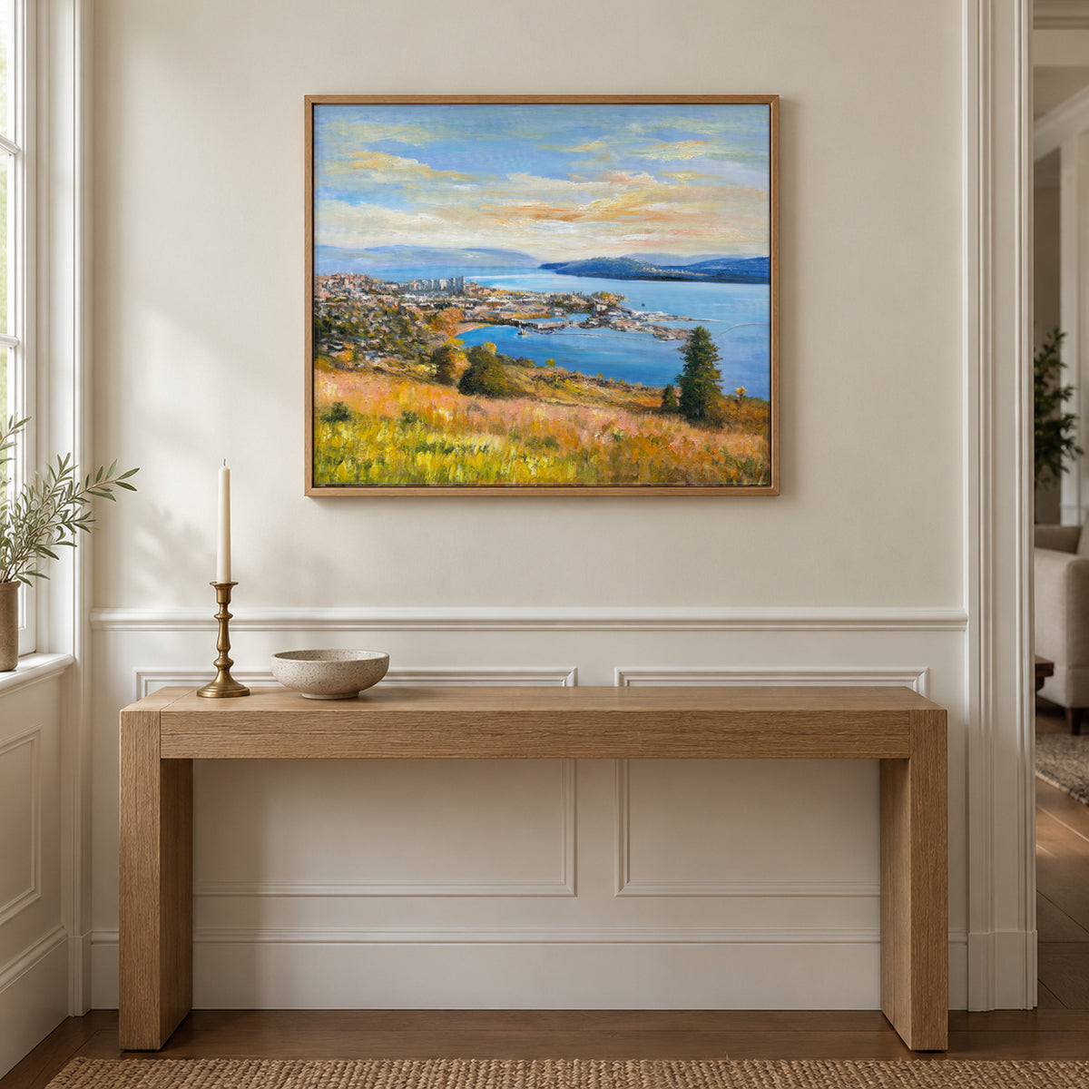 Okanagan Lake at Knox Mountain by Yingzhi Chen hanging on a creamy ivory wainscoting wall with white panelling below above a white-oak console with a brass candlestick and a small bowl